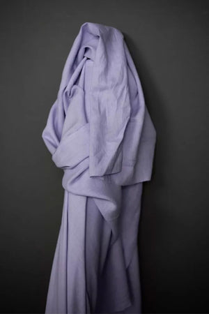 a roll of European laundered linen in soft lilac, on a dark grey background.