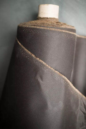 Close-up of dark brown oilskin fabric on a gray background