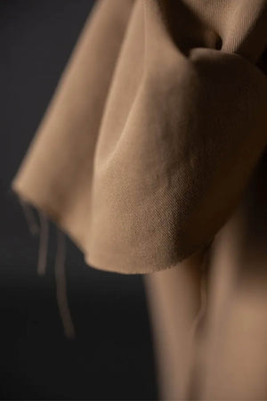 close up of tan fabric roll against a black wall