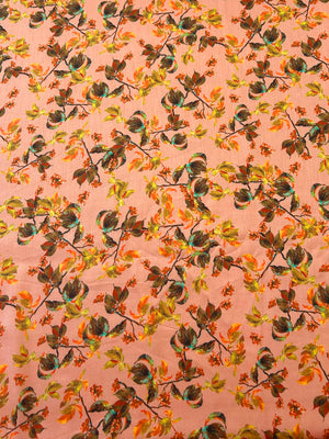 Leafy pattern with green, orange, and brown leaves on a peach background.
