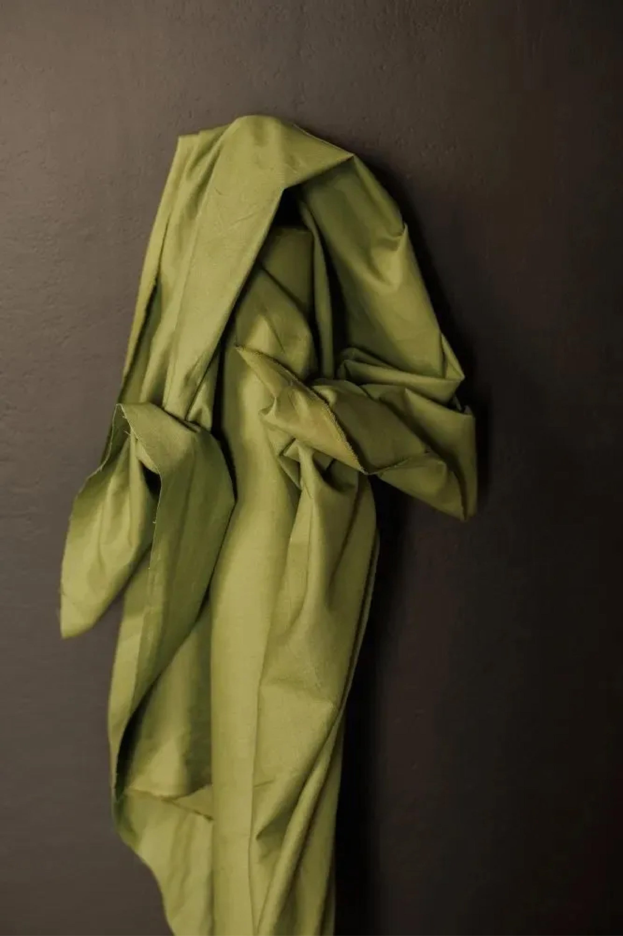 soft cotton canvas fabric in a classic leafy green color with a matte finish on a dark grey background.
