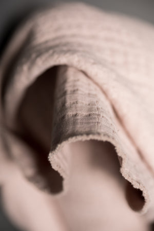 close up pale pink jacquard fabric with a dark grey background