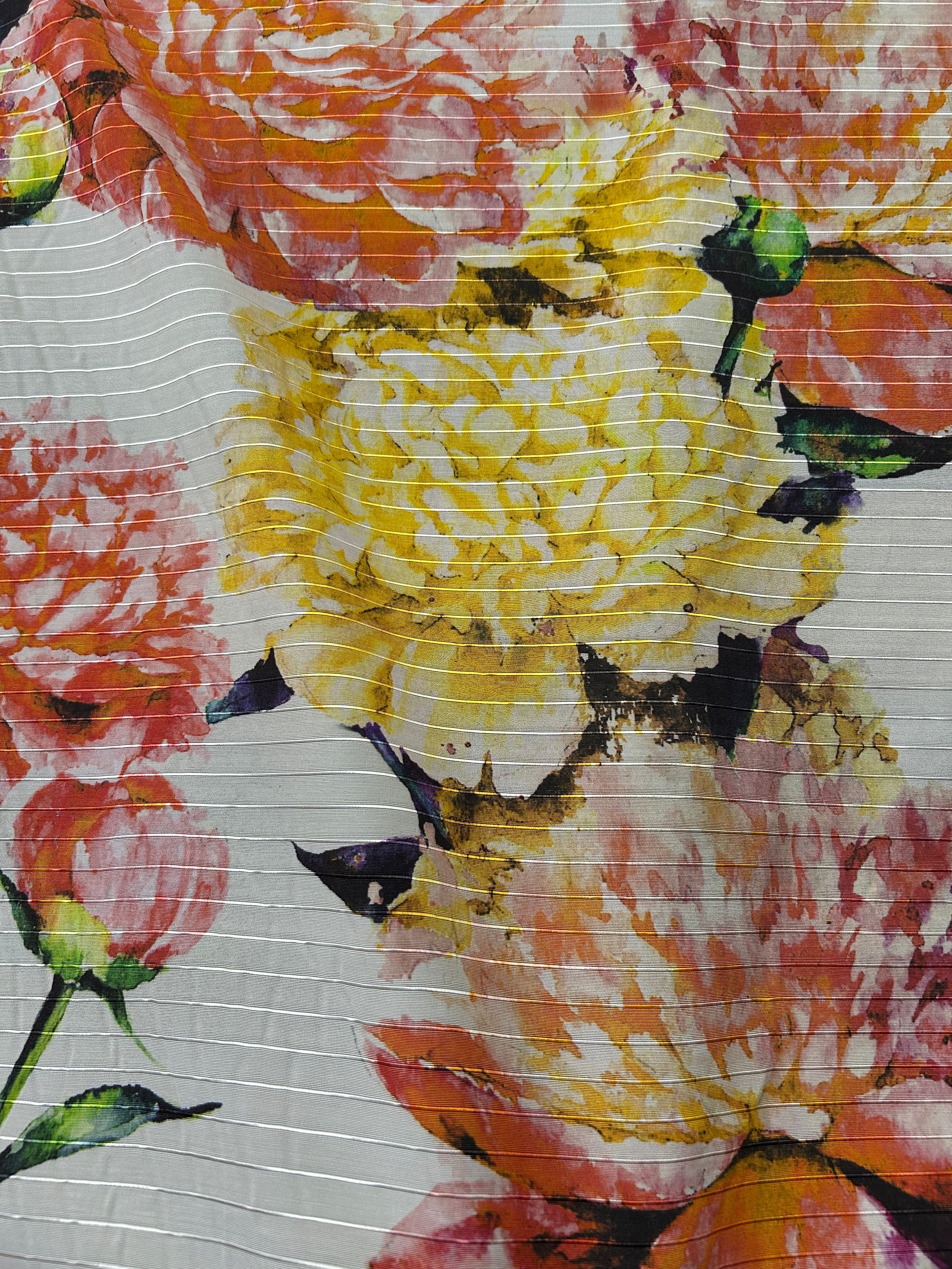 Floral patterned fabric with large flowers in orange, yellow, and red on a white background.