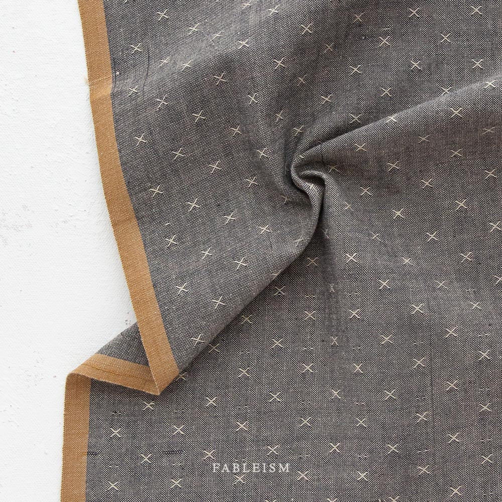 100% cotton fabric in a stunning weave of white and grey brown giving it pepper color. It is patterned and slightly textured with a small woven "x". With a light brown selvage.