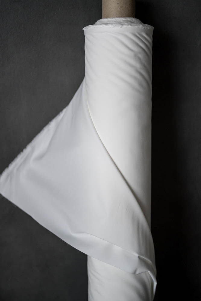 Roll of Cotton Percale Fabric in white on a dark grey background.