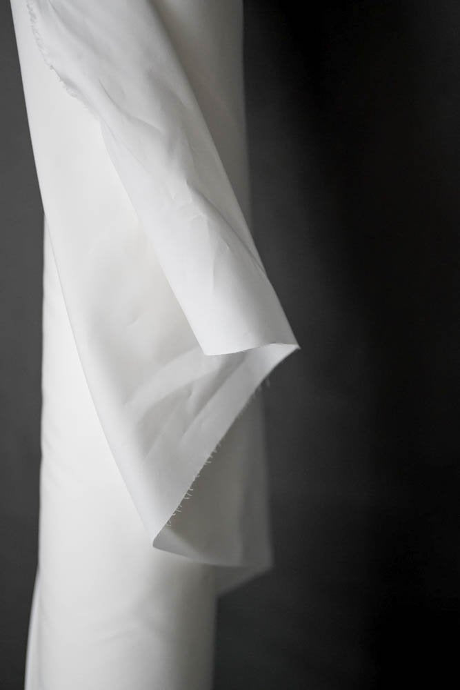 Roll of Cotton Percale Fabric in white on a dark grey background.