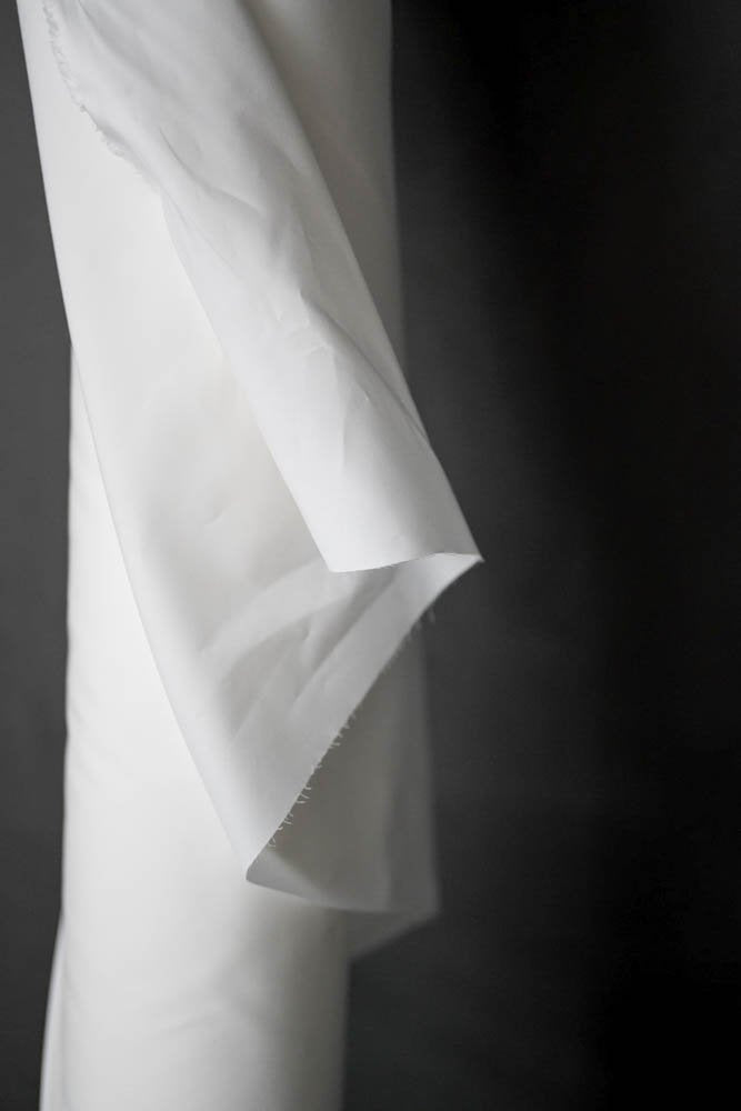 Close up of a cotton percale in white fabric on a dark grey background.