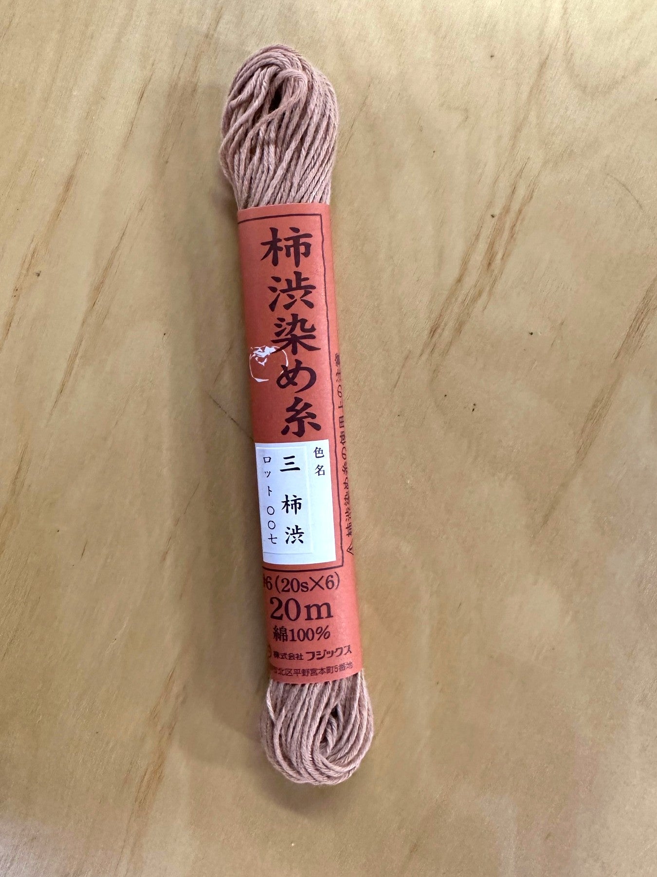 Spool of pink thread with a label on a wooden surface