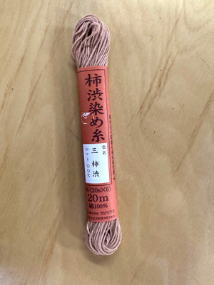 Spool of pink thread with a label on a wooden surface