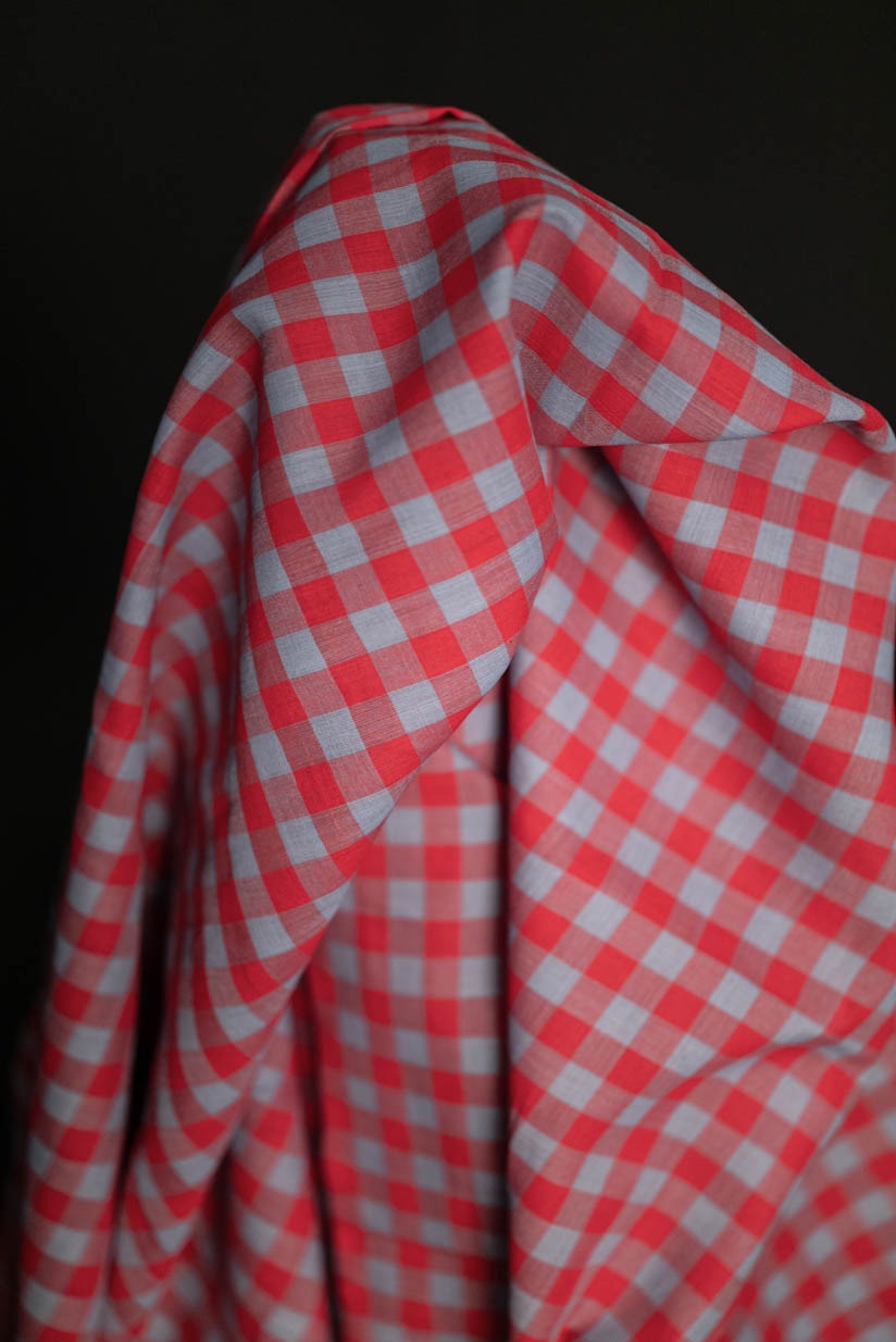 A vibrant pinky red and sky blue check indian cotton fabric on a black background