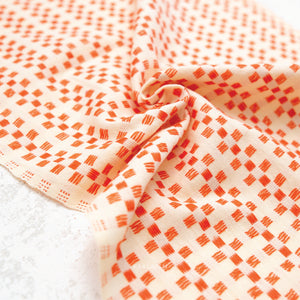 100% cotton fabric with a charming woven textured checkered pattern in orange on a cream background.