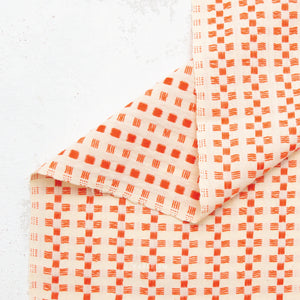 100% cotton fabric with a charming woven textured checkered pattern in orange on a cream background.