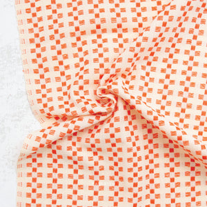 100% cotton fabric with a charming woven textured checkered pattern in orange on a cream background.