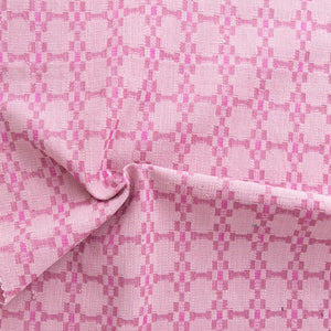 Close-up of pink fabric with a subtle check pattern