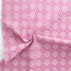 Close-up of pink fabric with a checkered pattern on a white background