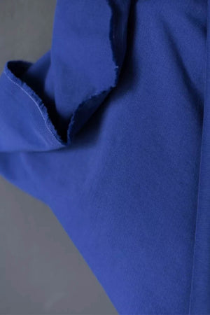 close up of blue fabric roll by a white wall