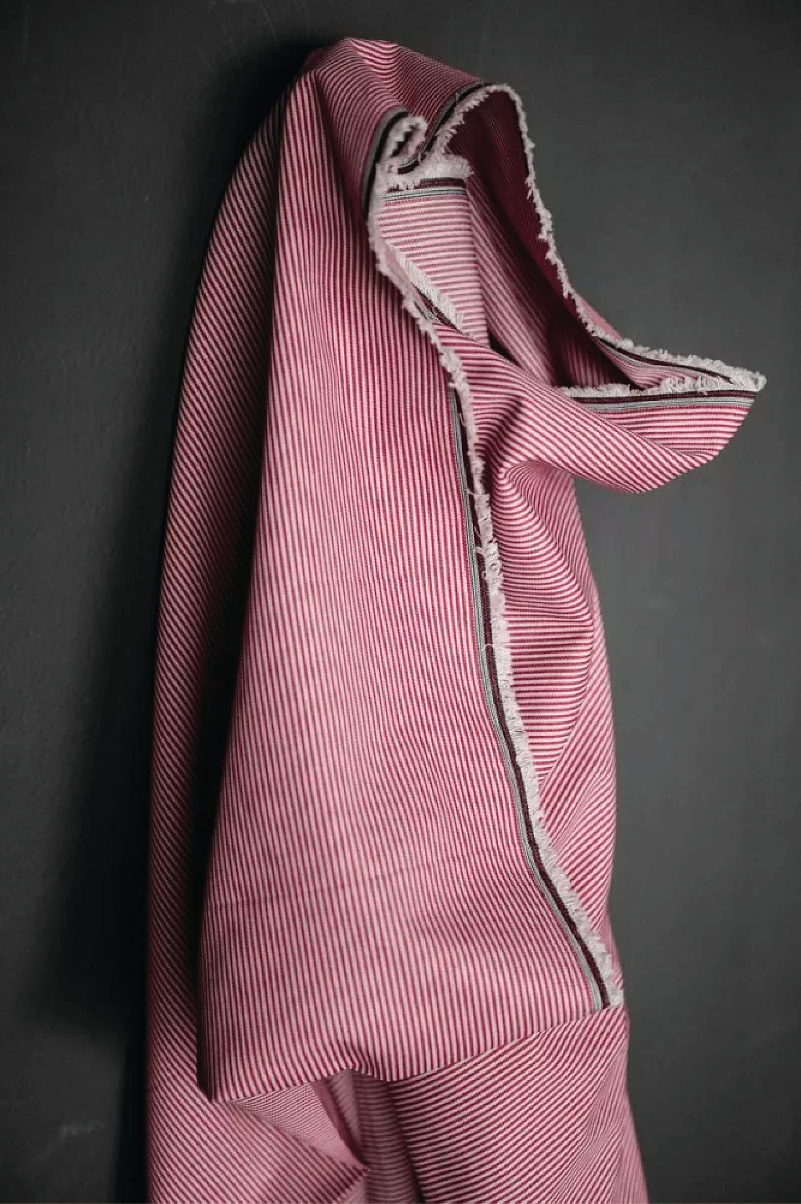 A thin red and white stripe fabric on a dark grey background.