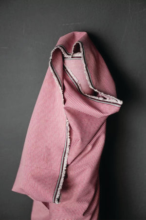A thin red and white stripe fabric on a dark grey background.