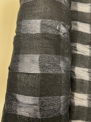close up of raw silk black checks on a roll.