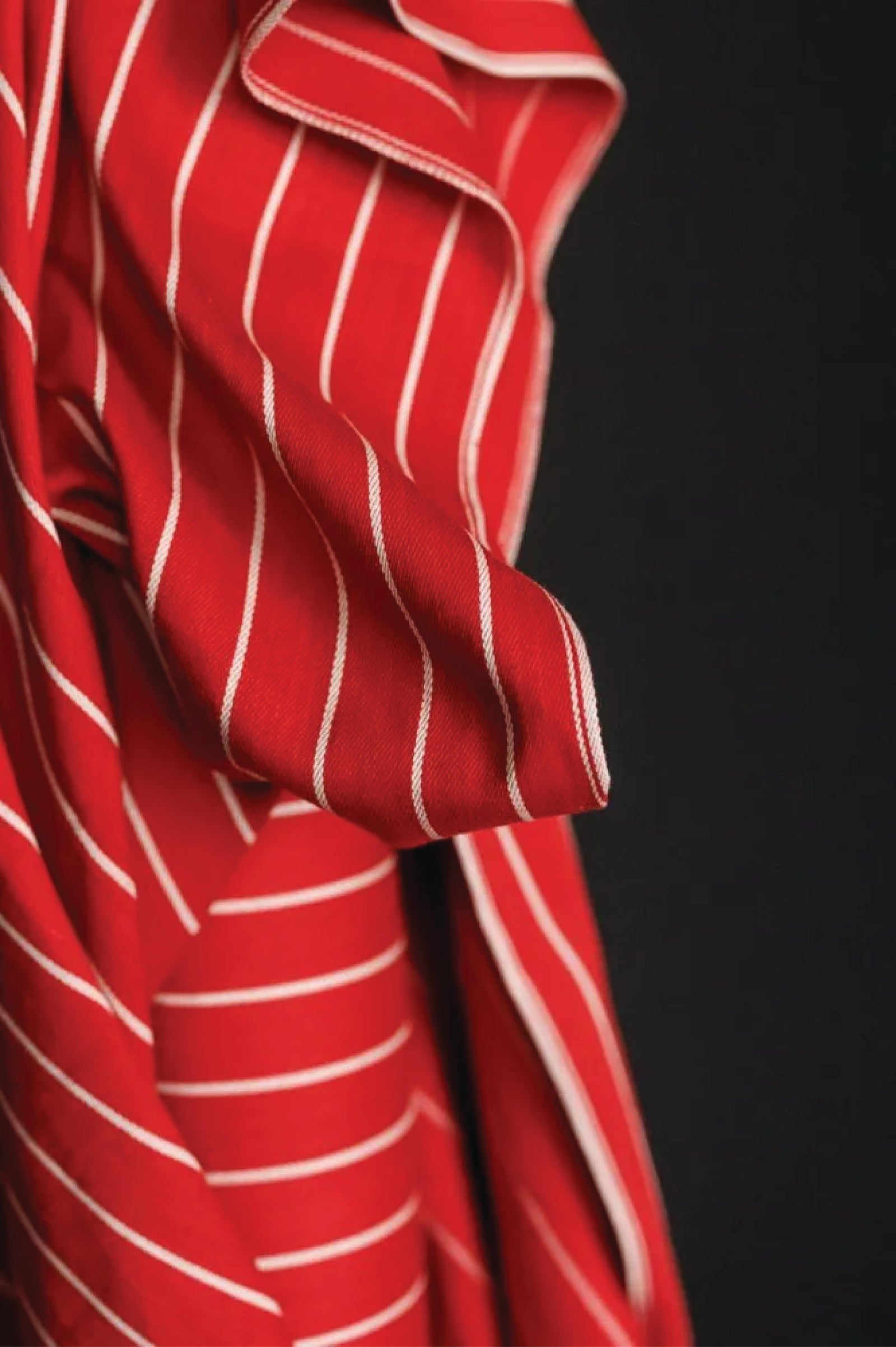 A wide red and think white striped fabric on a dark grey background.