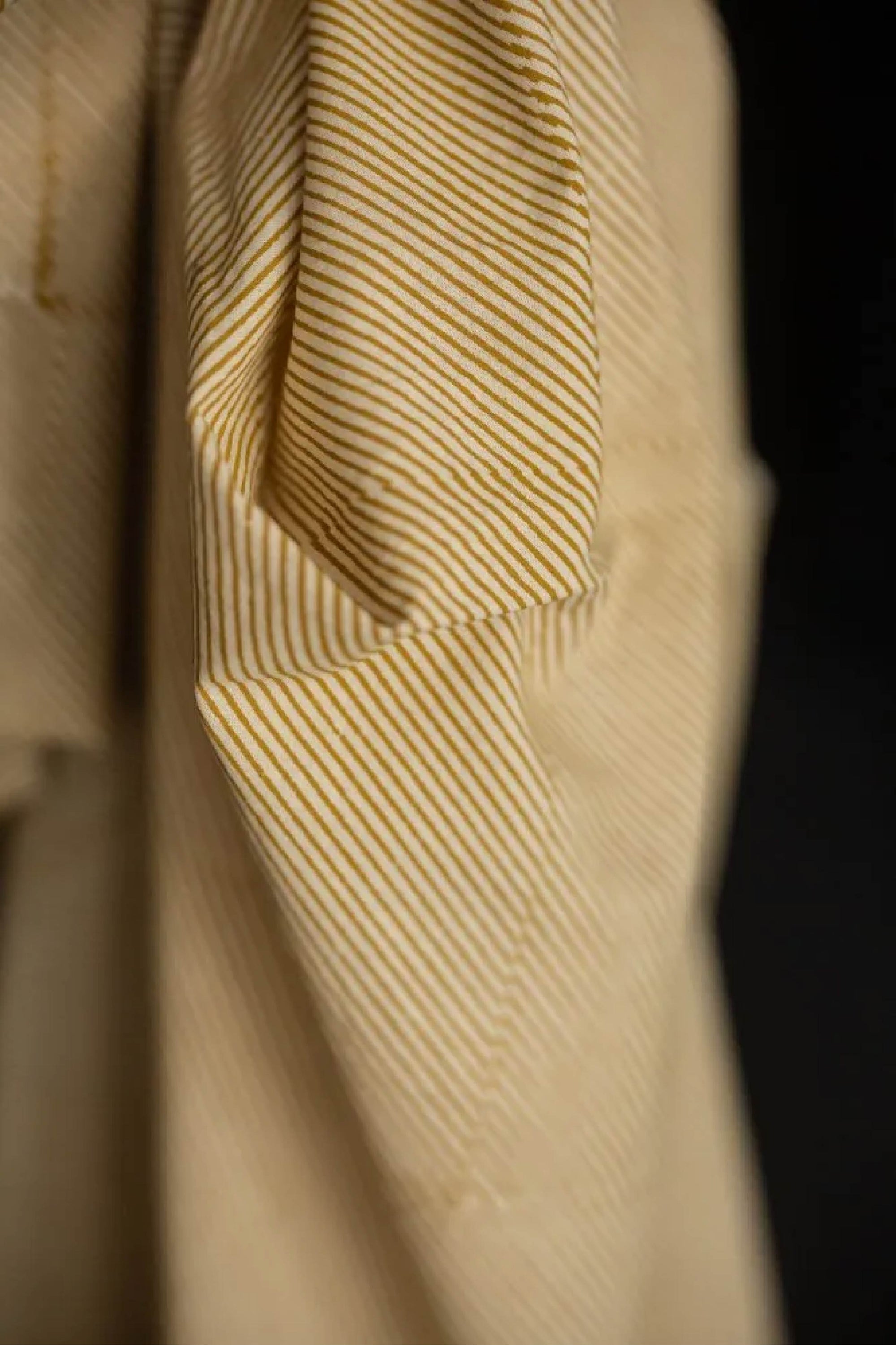 Close-up of a textured mustard orange cotton fabric with a dark background