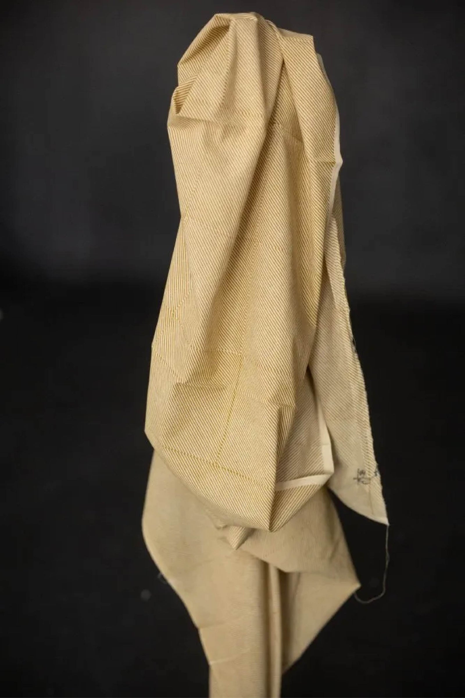 Close-up of a textured mustard orange cotton fabric with a dark background