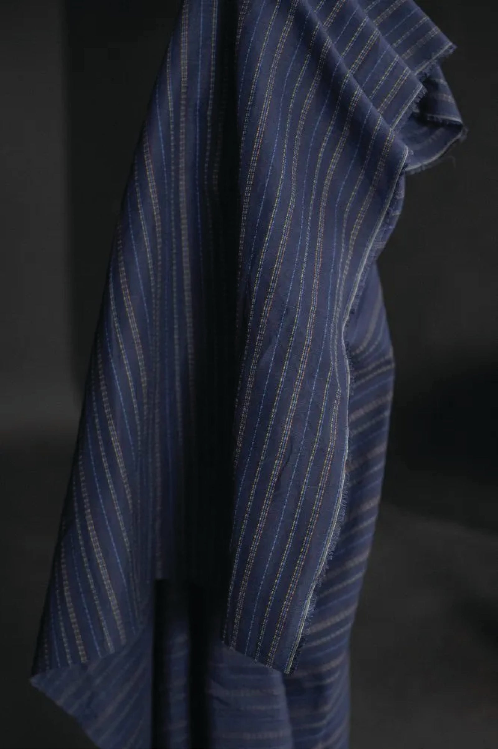 linen/cotton blend in a dark blue fabric with green, blue and tan stitch detail running parallel to the selvedge