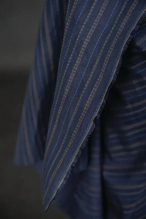 linen/cotton blend in a dark blue fabric with green, blue and tan stitch detail running parallel to the selvedge
