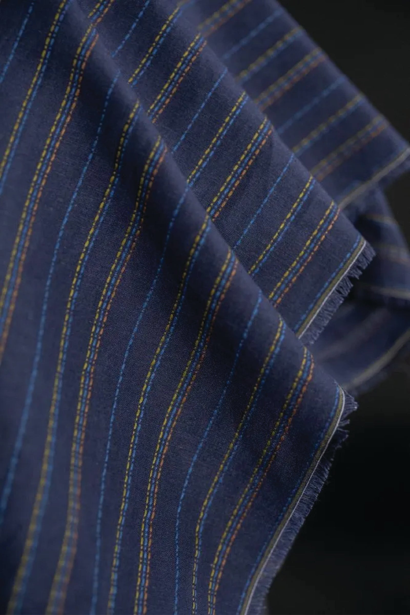 linen/cotton blend in a dark blue fabric with green, blue and tan stitch detail running parallel to the selvedge