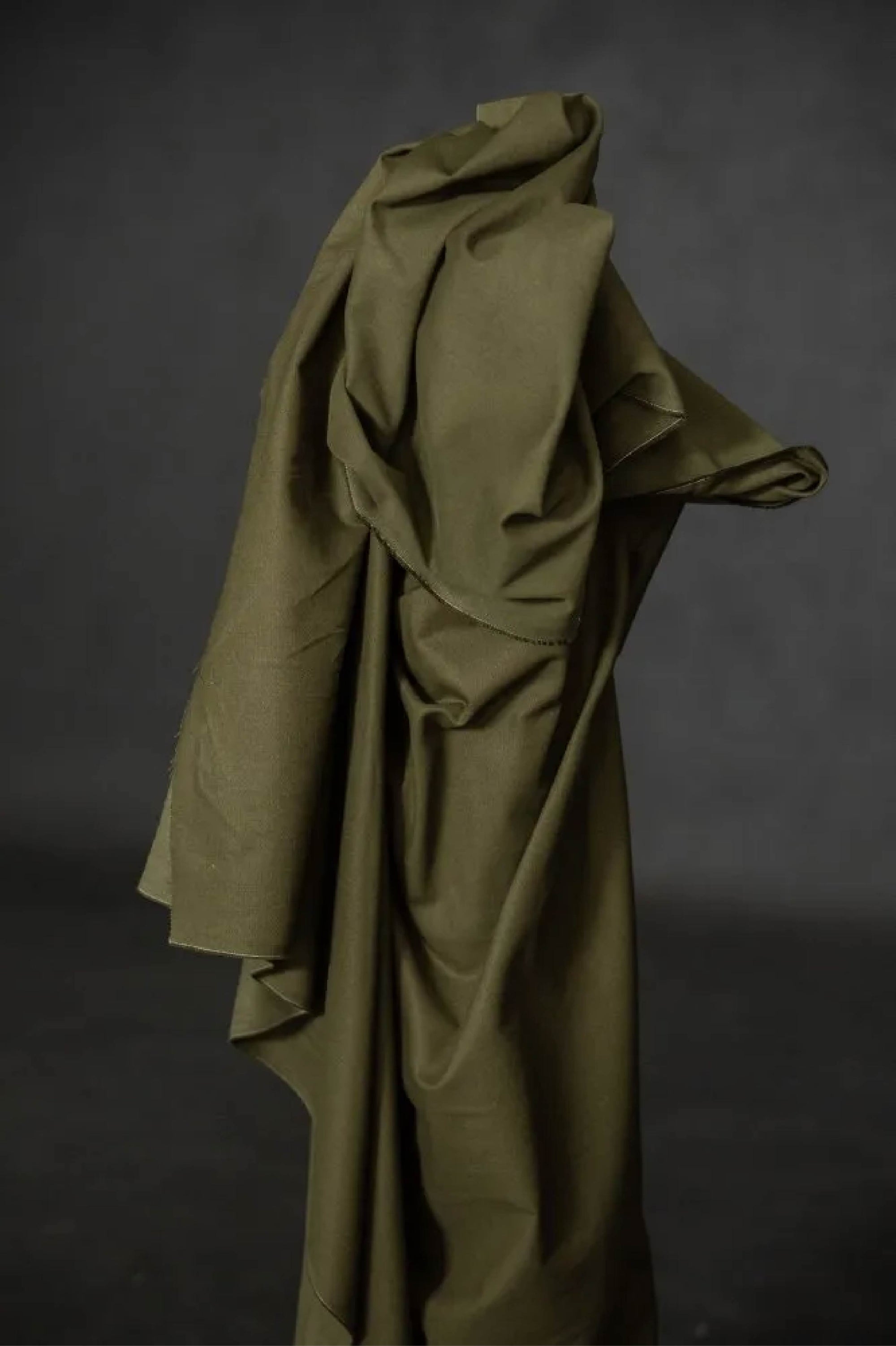 dark green fabric roll against a dark wall