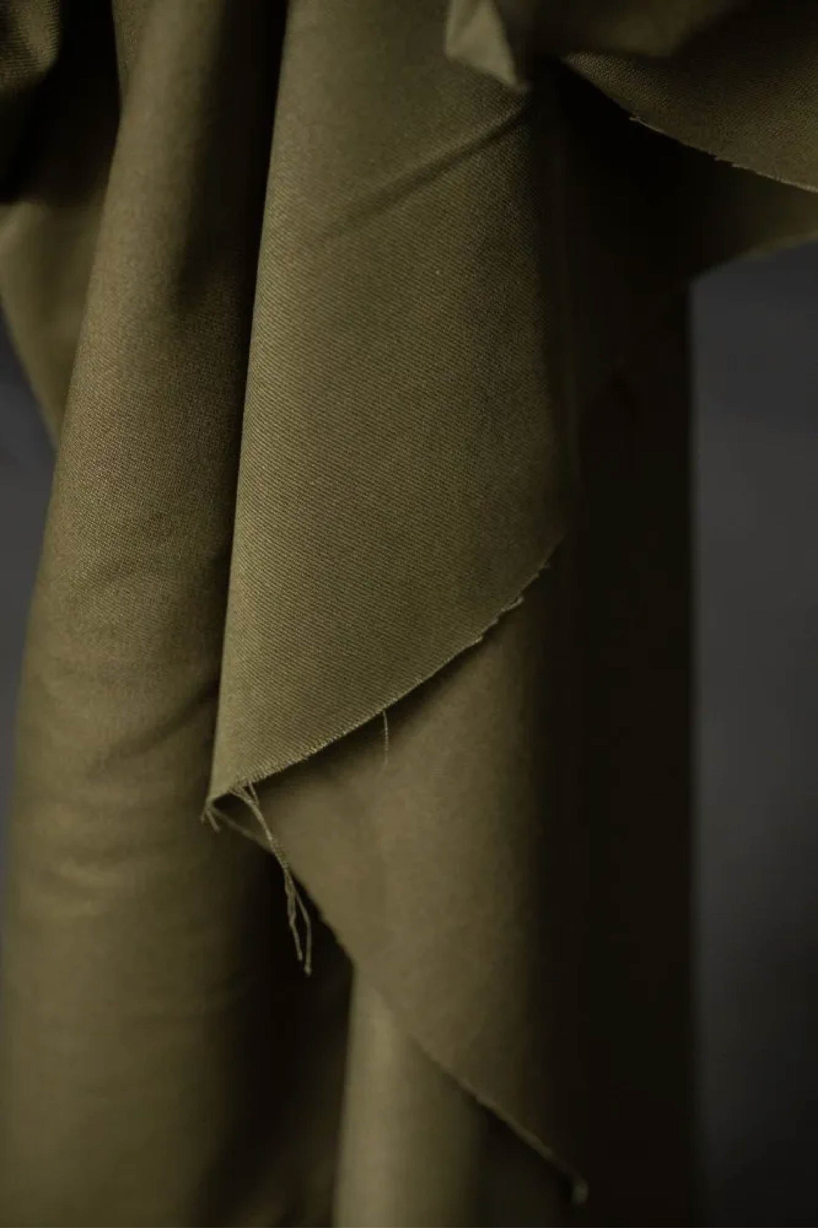 dark green fabric roll against a dark wall