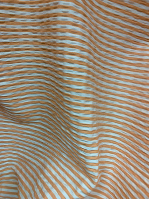 close up of a draped cotton seersucker fabric in a horizontal striped Orange and White 