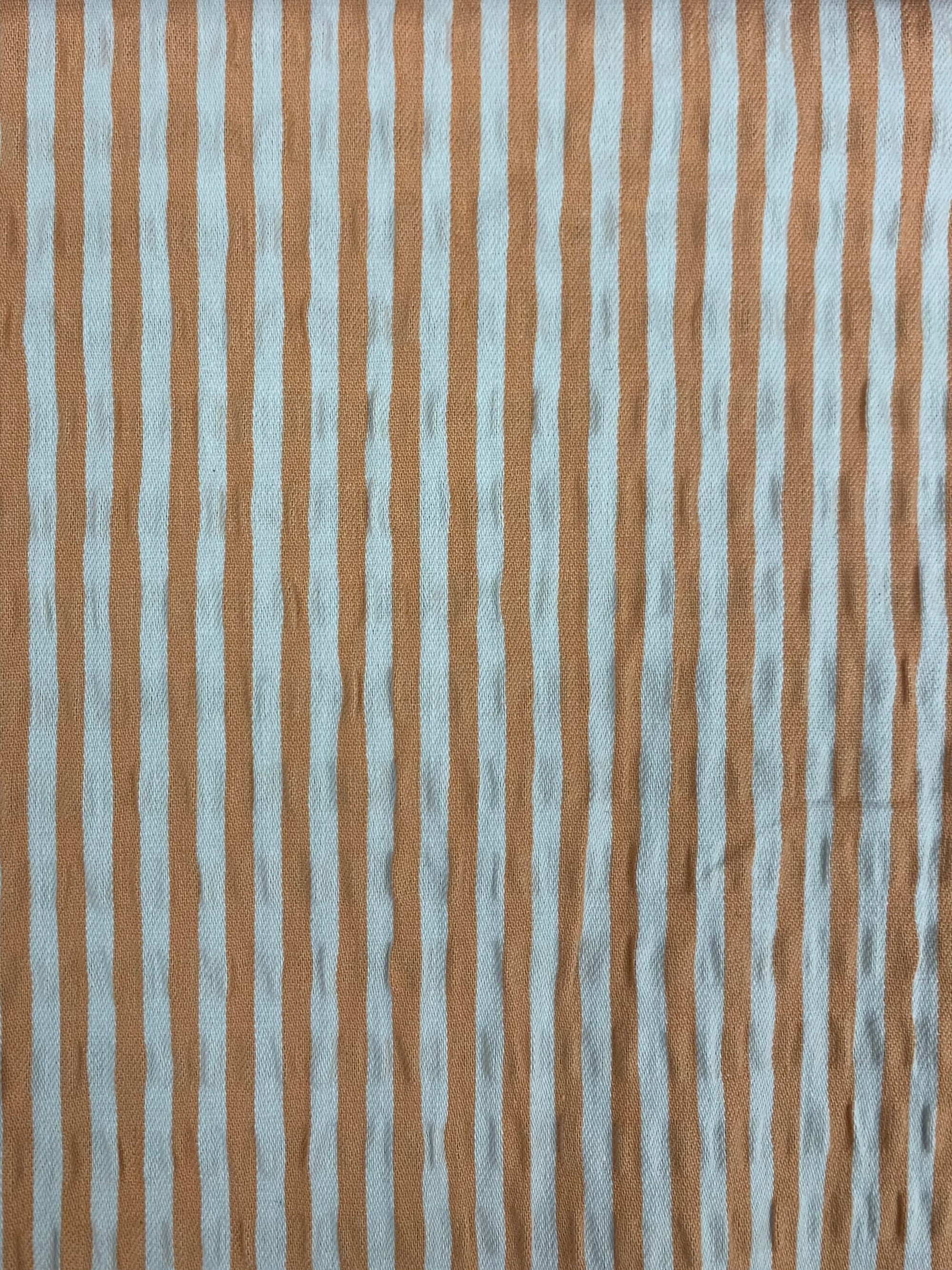 A close up of cotton seersucker fabric in a vertical striped Orange and White