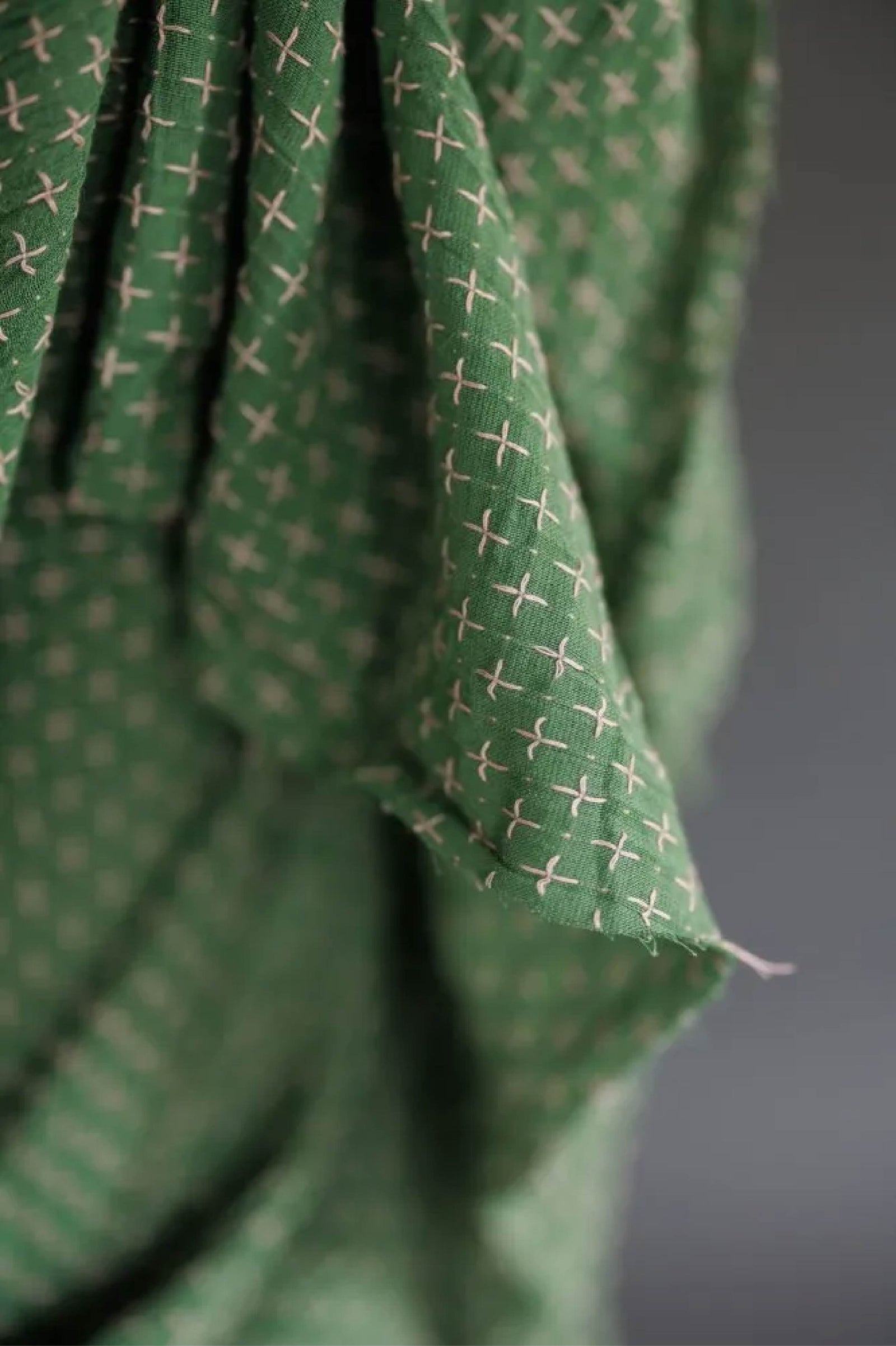 Close-up of green fabric with a subtle pattern on a dark background