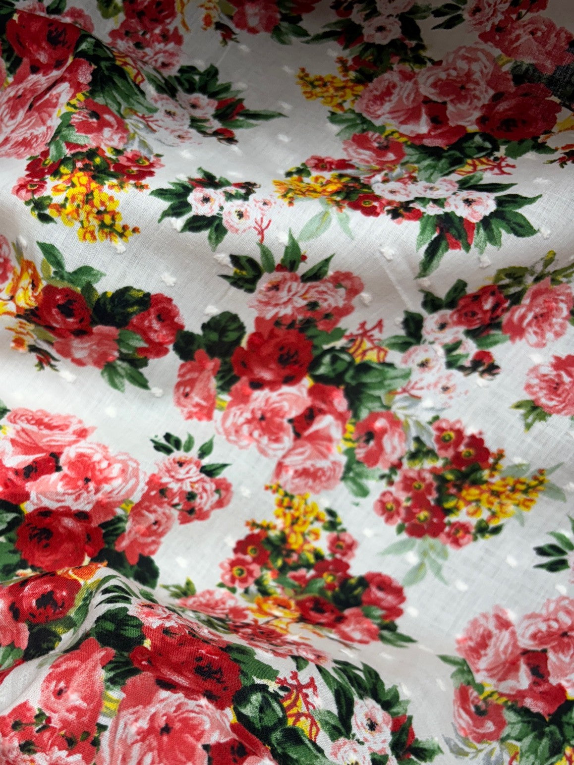 Close-up of floral fabric with red, pink, and yellow flowers on a white background