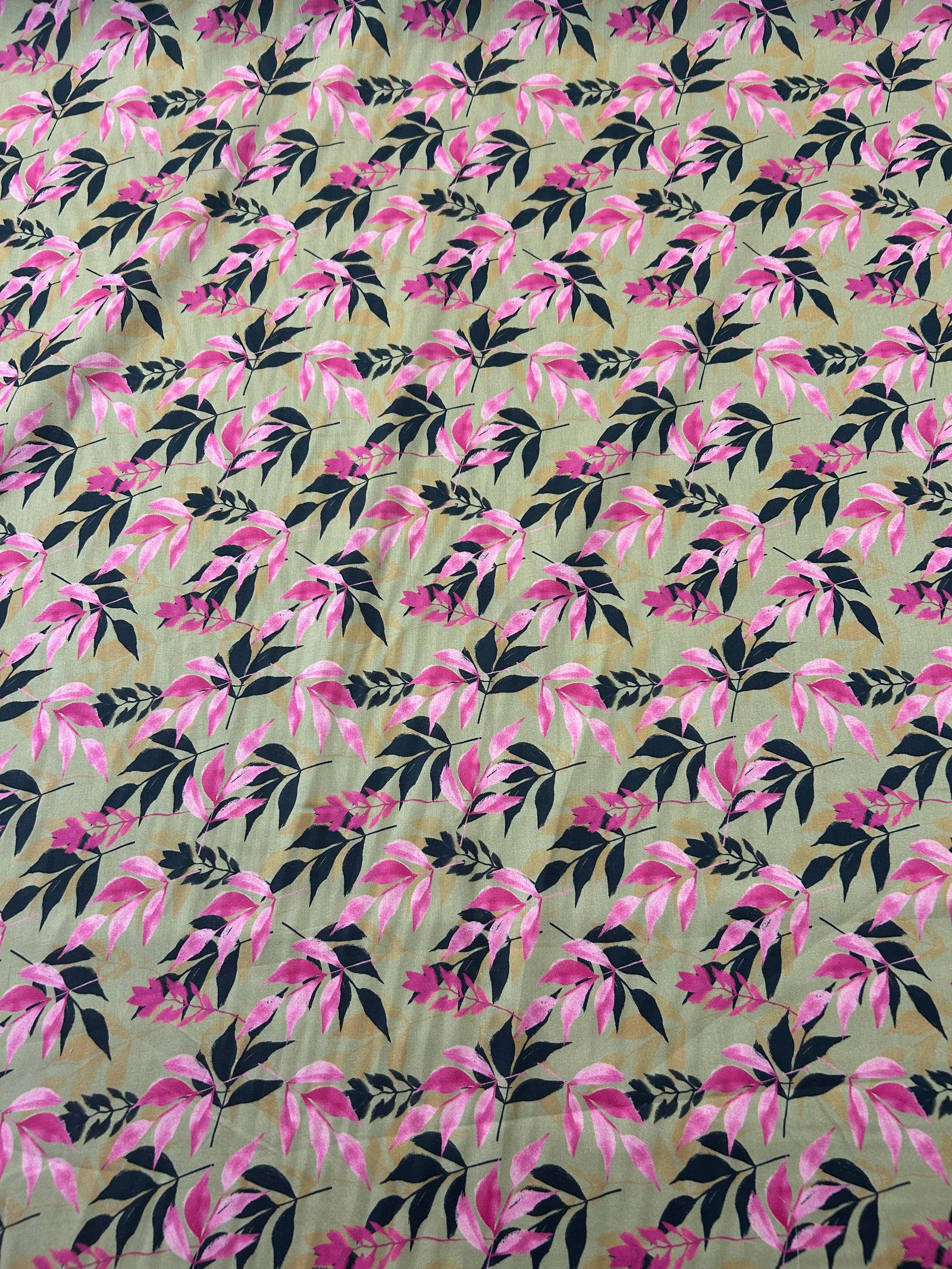 Fabric with pink and a black silhouette leaf pattern on tan background. In a swirl.