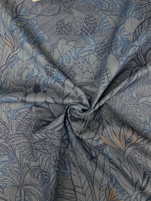 Spiraled Cotton chambray fabric with a tropical blue print with touches of orange on a denim blue background 