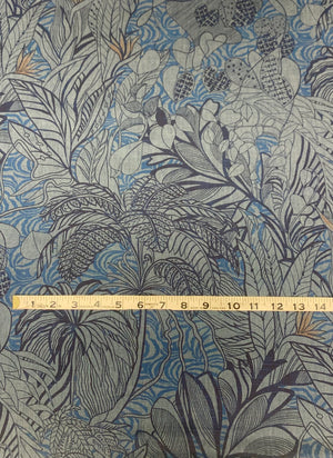 Cotton chambray fabric with a tropical blue print with touches of orange on a denim blue background and a measuring tape on top of the fabric.