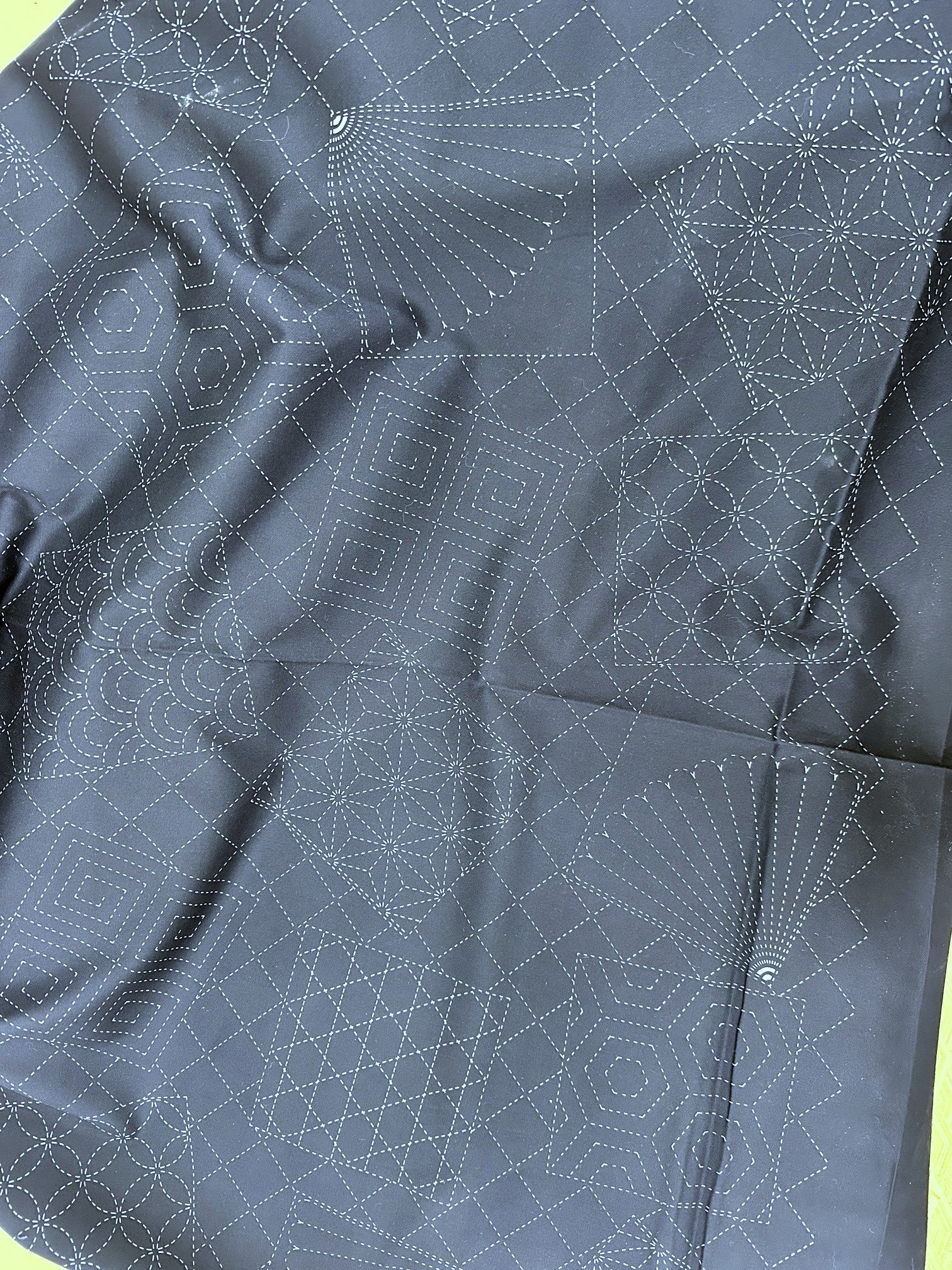 Dark blue fabric with white geometric stitching pattern, measured against a yellow ruler.