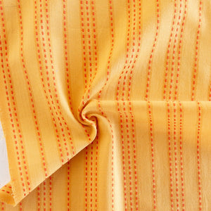 Close-up of yellow fabric with red stitching