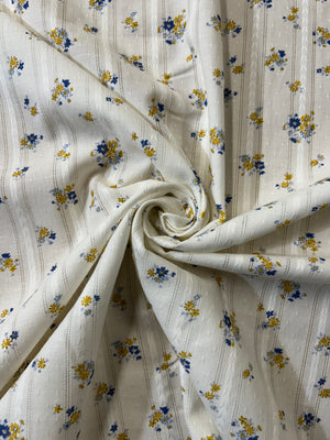 cotton fabric with a vintage blue and mustard floral print with embroidered vertical stripes in a spiral.