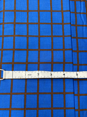organic cotton lawn in blue with a deep auburn window pane check with measuring tape on top.