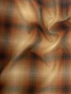A beautiful soft light to medium-weight yarn dyed wool in a pretty plaid (light brown, black, and deep orange). 