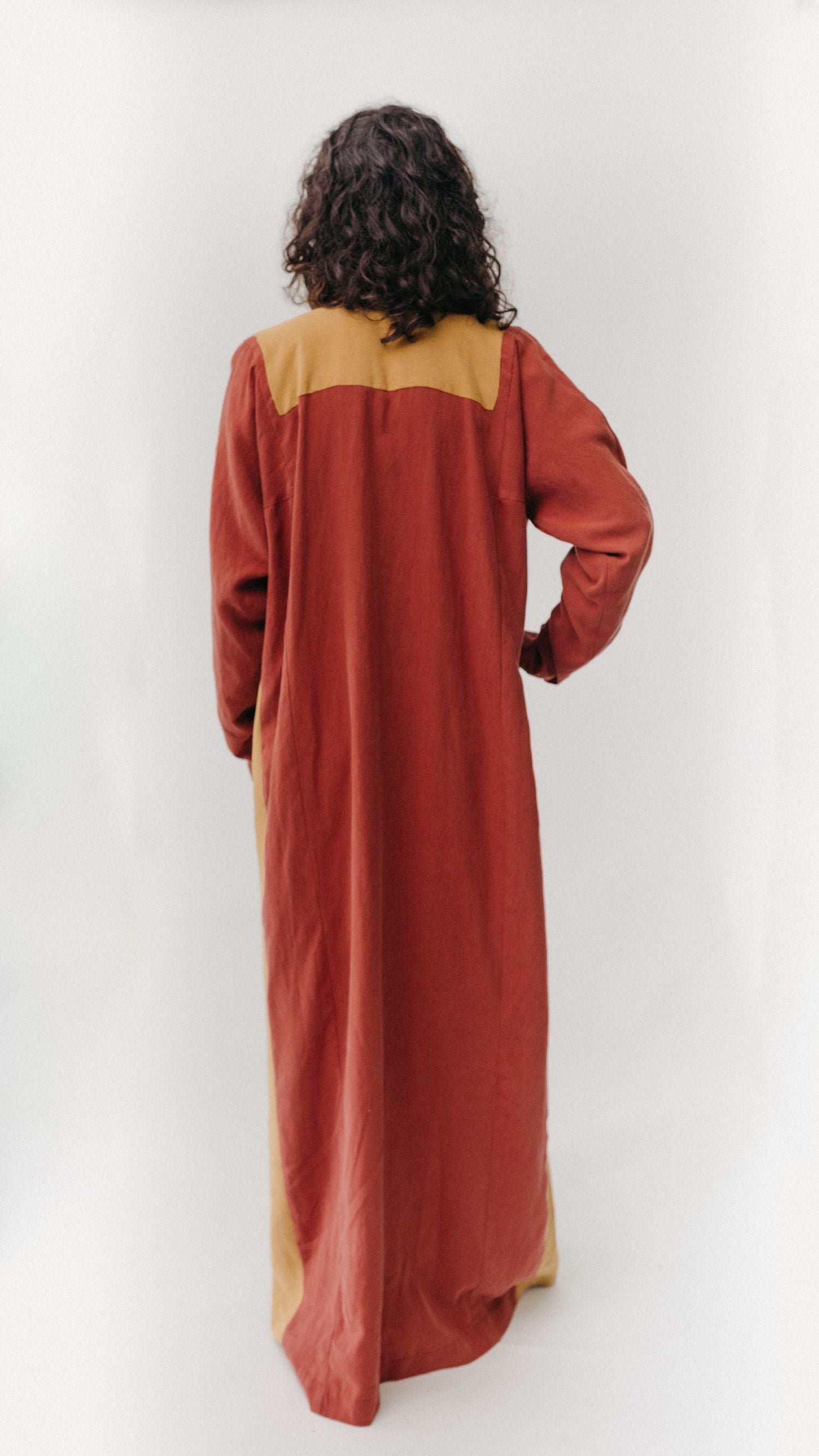 Back View of Gaza Dress. Woman wearing floor length red dress with mustard yellow yoke.