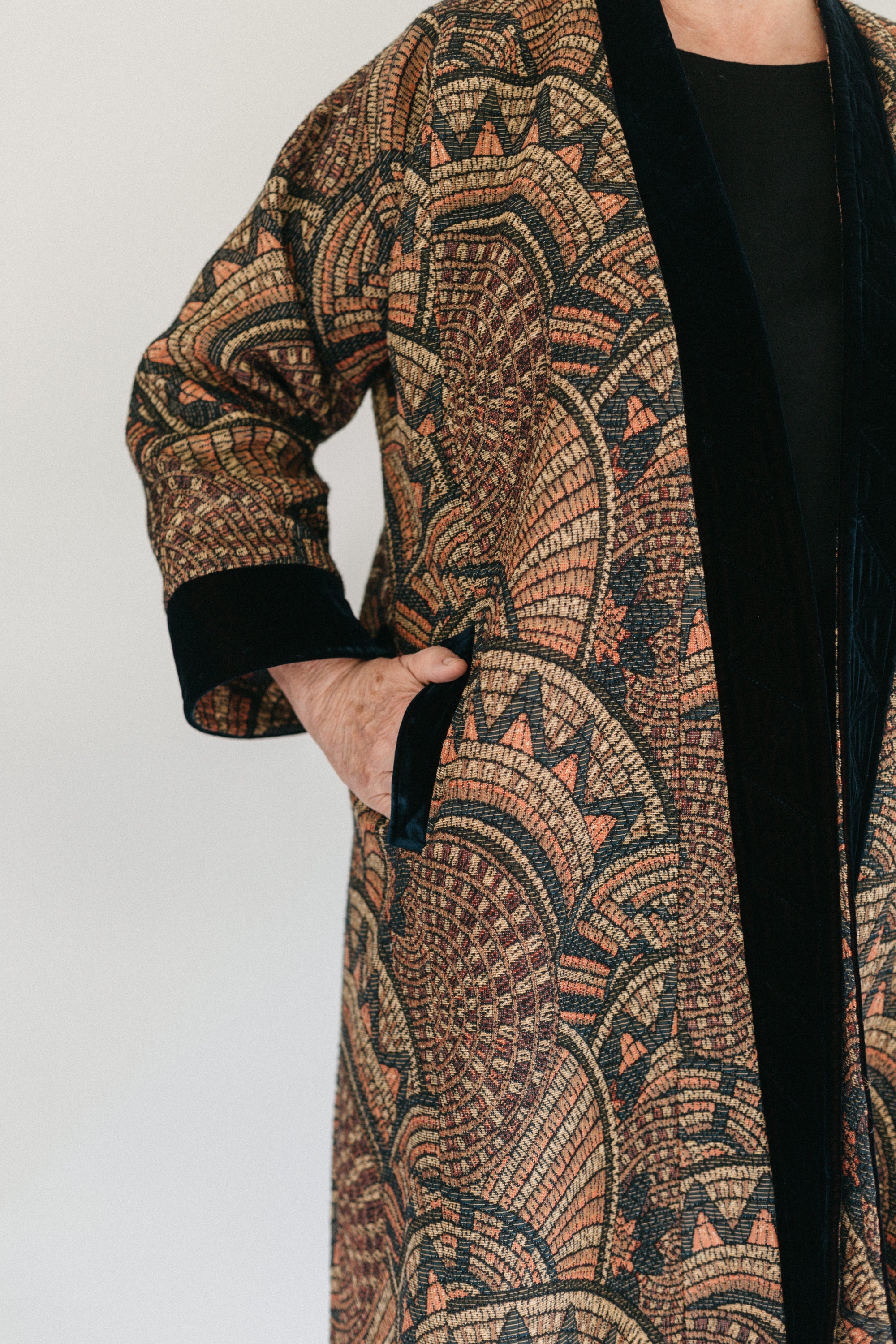 Close up of Turkish coat with view of side pocket.  Model has hand partially in pocket.