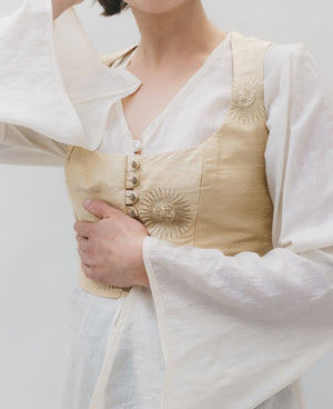 Close up photo of the vest and tunic (entari).  modle has one are mat waist and one raised to head highlighting the belled sleeves of the entari (tunic)