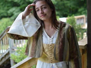Photo of young woman wearing all three pieces of the 108 Turkish dancer ensemble. Entari (tunic) under, Vest middle layer, Jacket over both layers.  Bell sleeve is highlighted with woman reaching up to touch hair. 