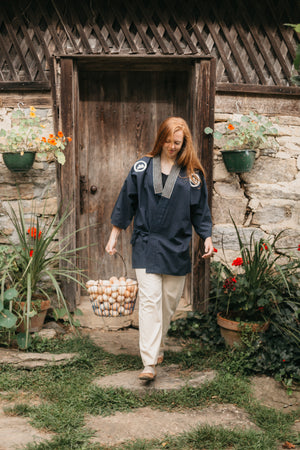 young woman wearing Japanese Field Clothing walking with a basket of eggs. 