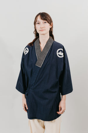 Japanese American woman wearing a navy Hippari with embroidery.  In front a a white background