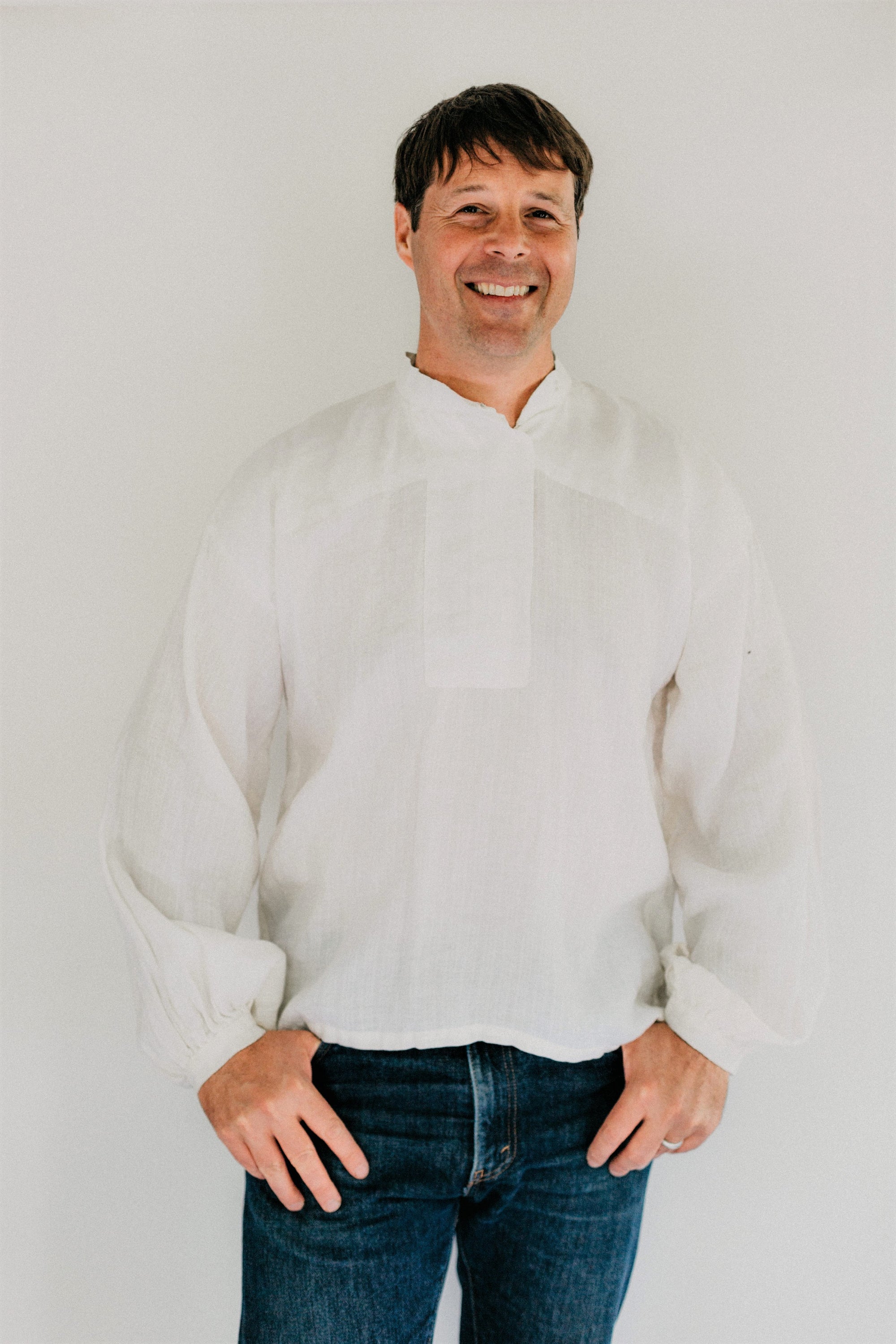 Man modeling View B a simple white cotton shirting.  He is wearing denim jeans and standing in front of a white backdrop.